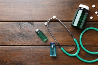 Photo of Pharmacist. Glass vials, stethoscope, bottle and pills on wooden table, flat lay. Space for text