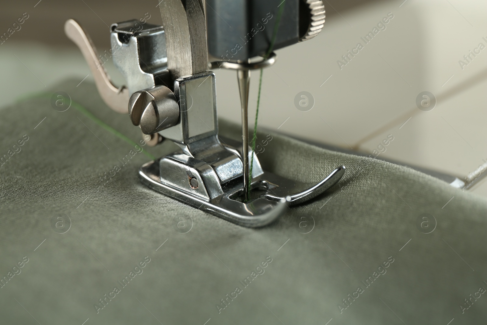 Photo of Sewing green fabric with machine, closeup view