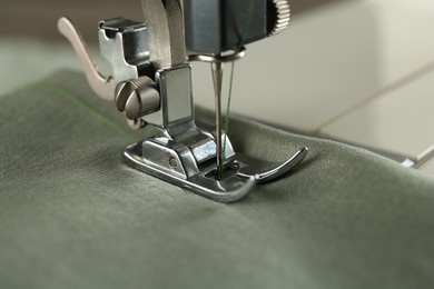 Sewing green fabric with machine, closeup view