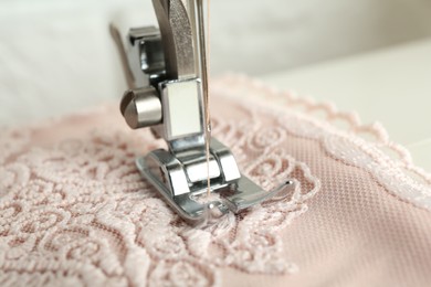 Photo of Sewing fabric with machine indoors, closeup view