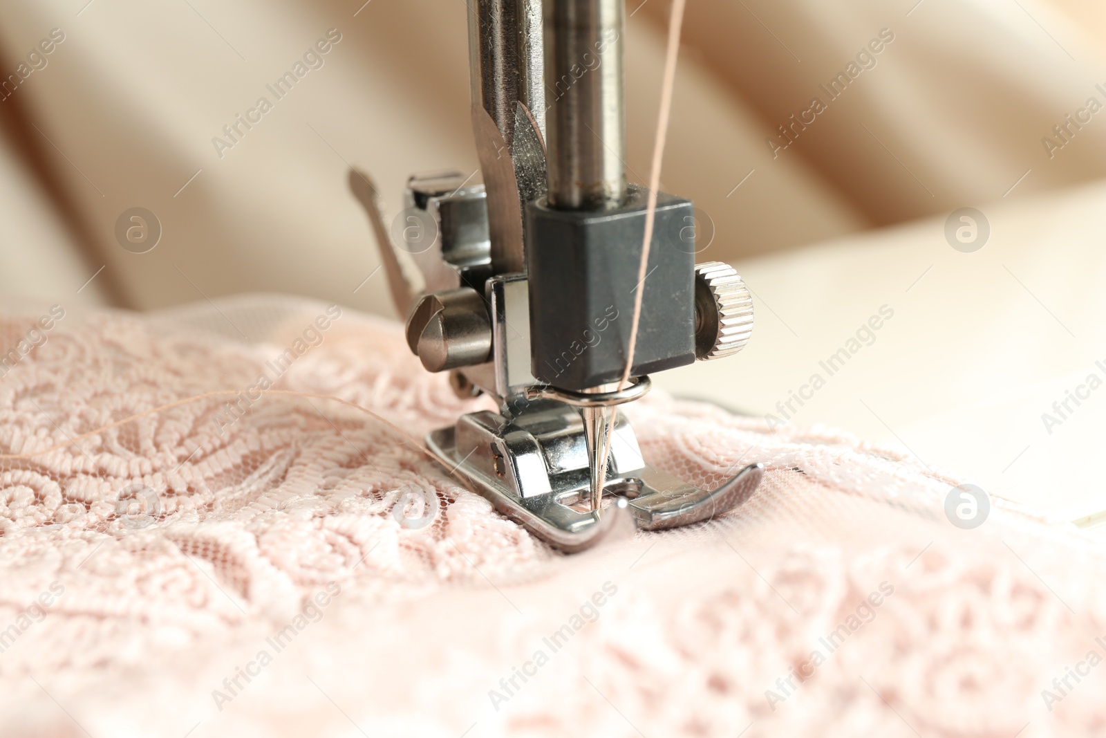 Photo of Sewing beige fabric with machine, closeup view