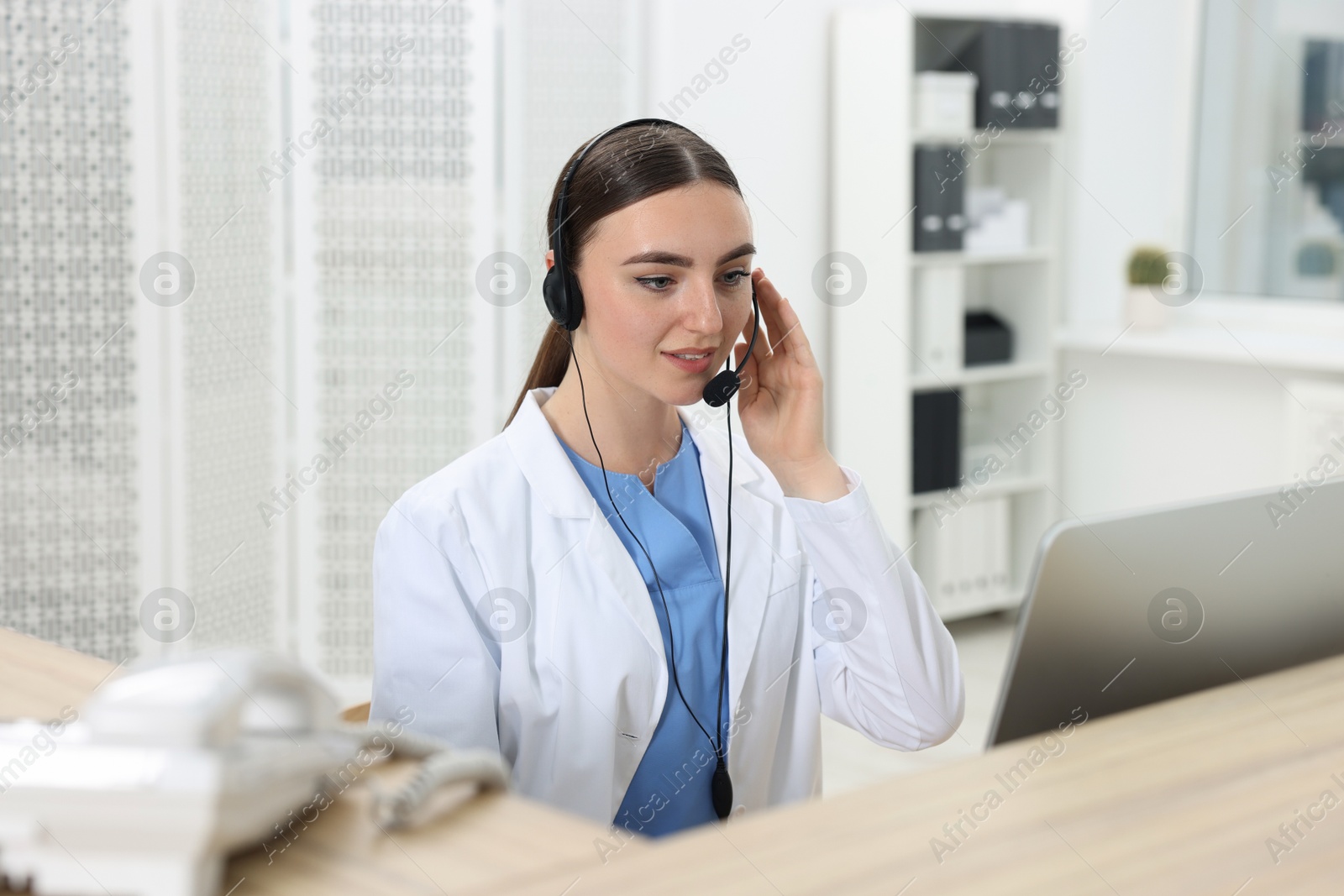 Photo of Professional receptionist working at wooden desk in hospital