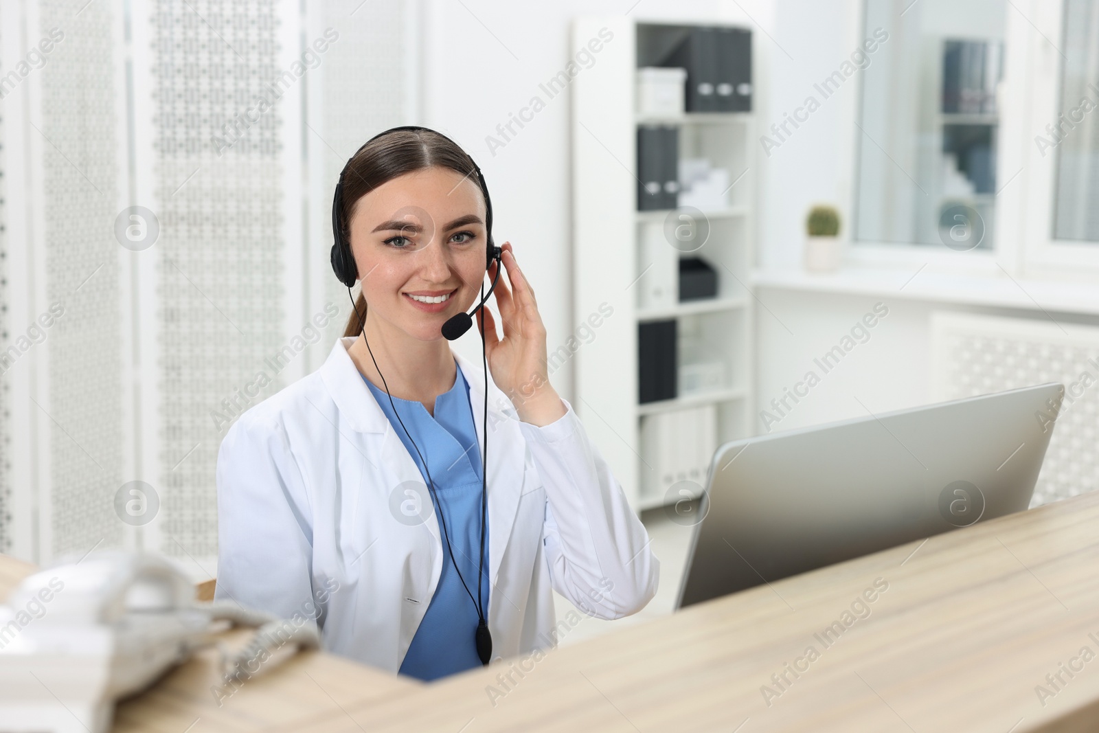 Photo of Professional receptionist working at wooden desk in hospital