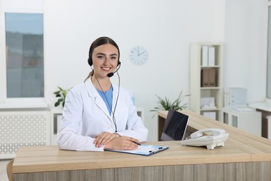 Photo of Professional receptionist working at wooden desk in hospital