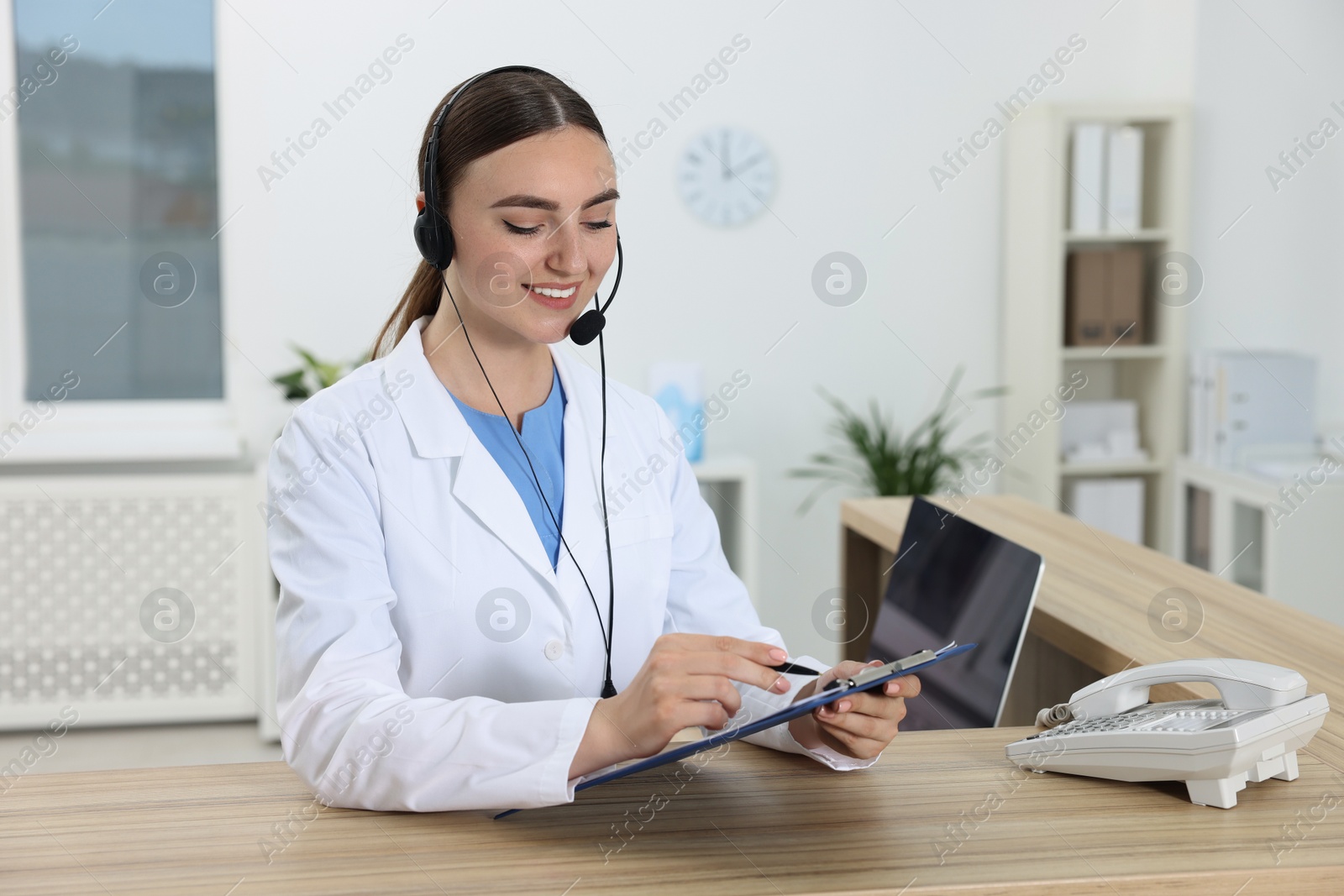 Photo of Professional receptionist working at wooden desk in hospital