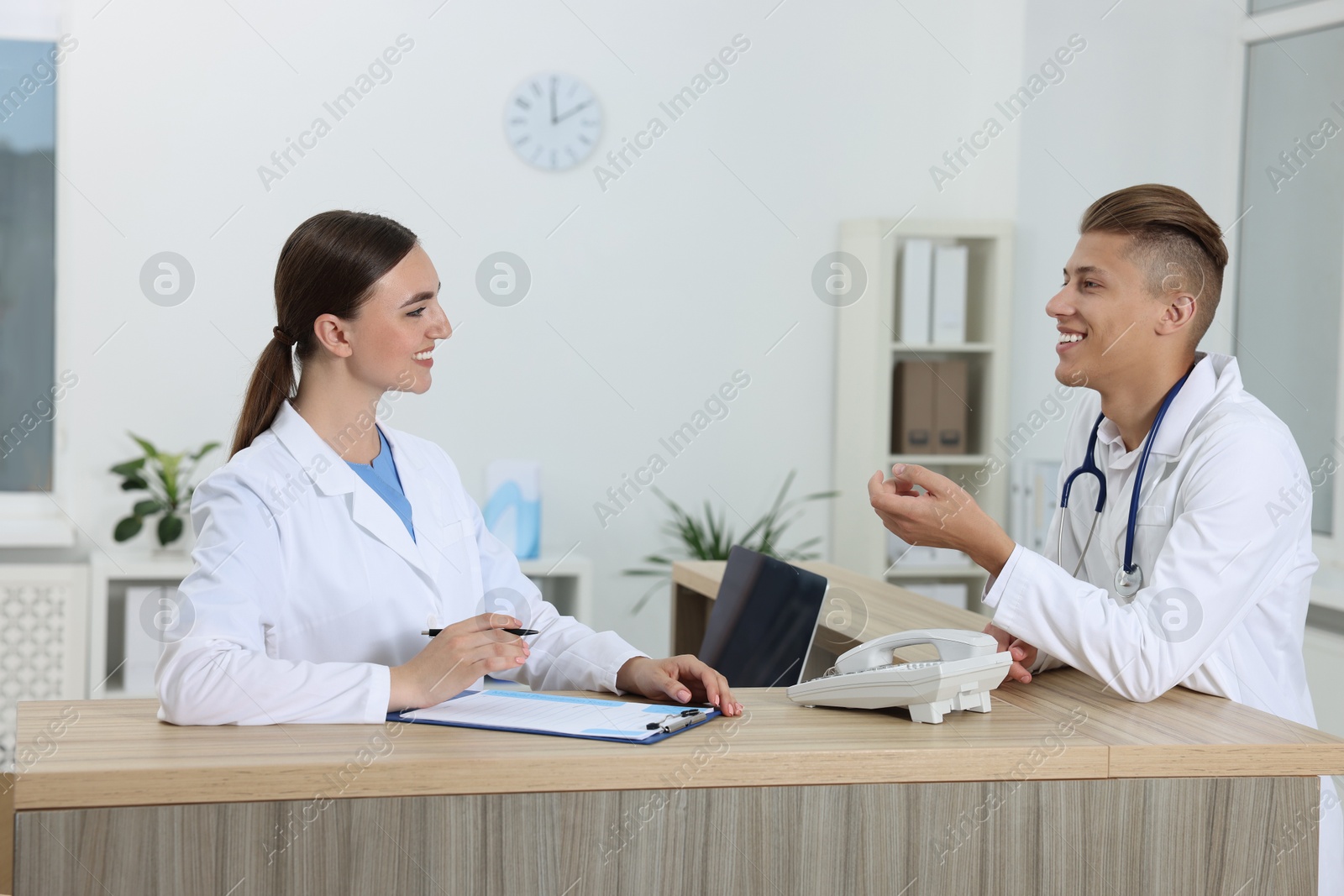 Photo of Professional receptionist and doctor at wooden desk in hospital