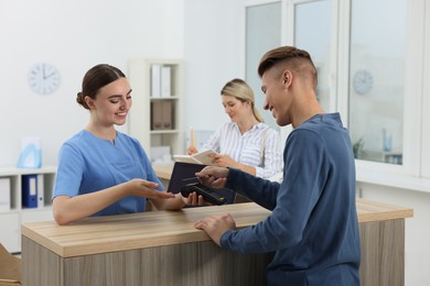 Receptionist taking payment from client via terminal at hospital