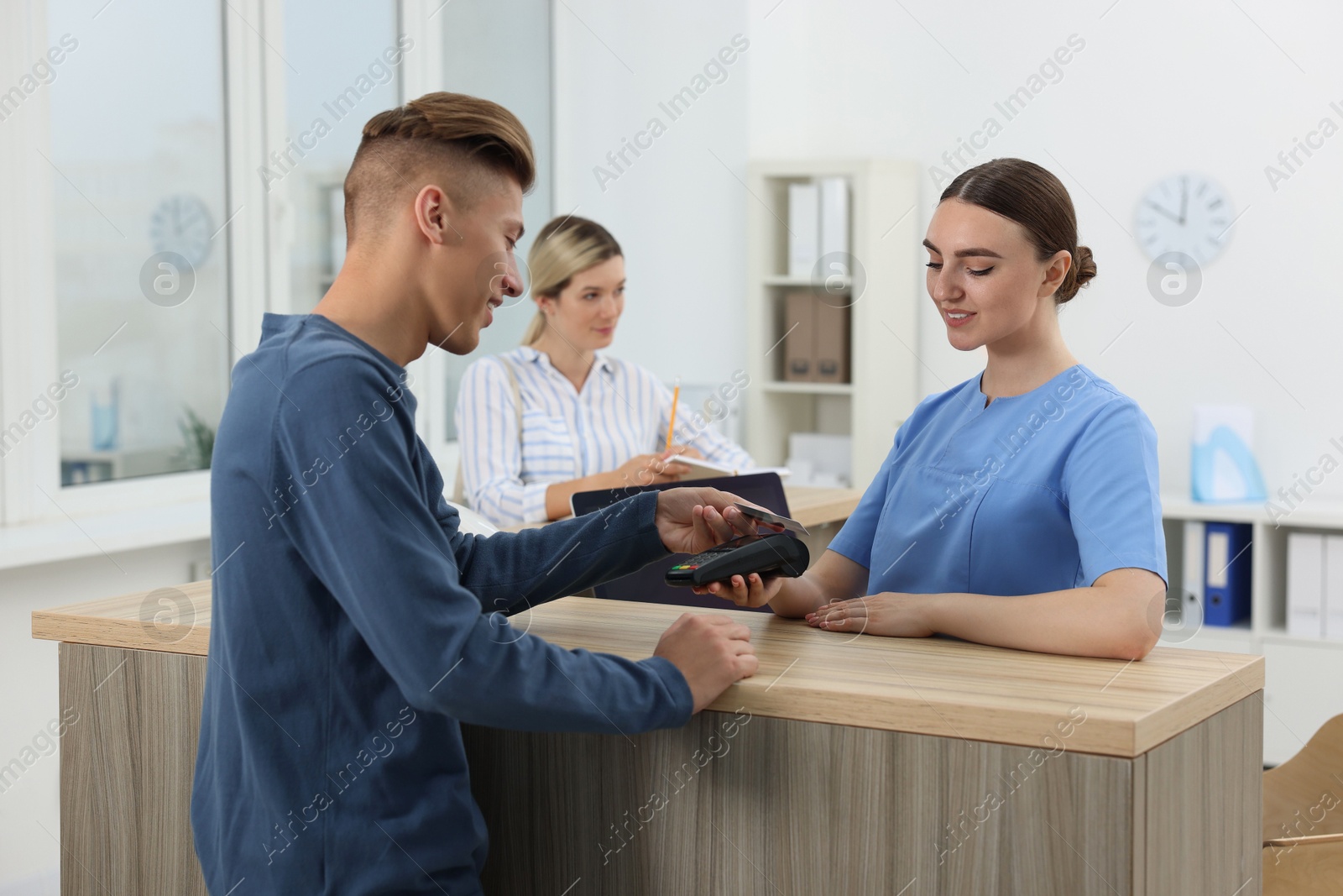 Photo of Receptionist taking payment from client via terminal at hospital