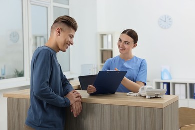 Photo of Professional receptionist working with patient at wooden desk in hospital