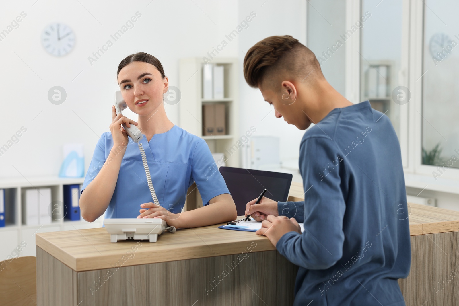 Photo of Professional receptionist working with patient at wooden desk in hospital