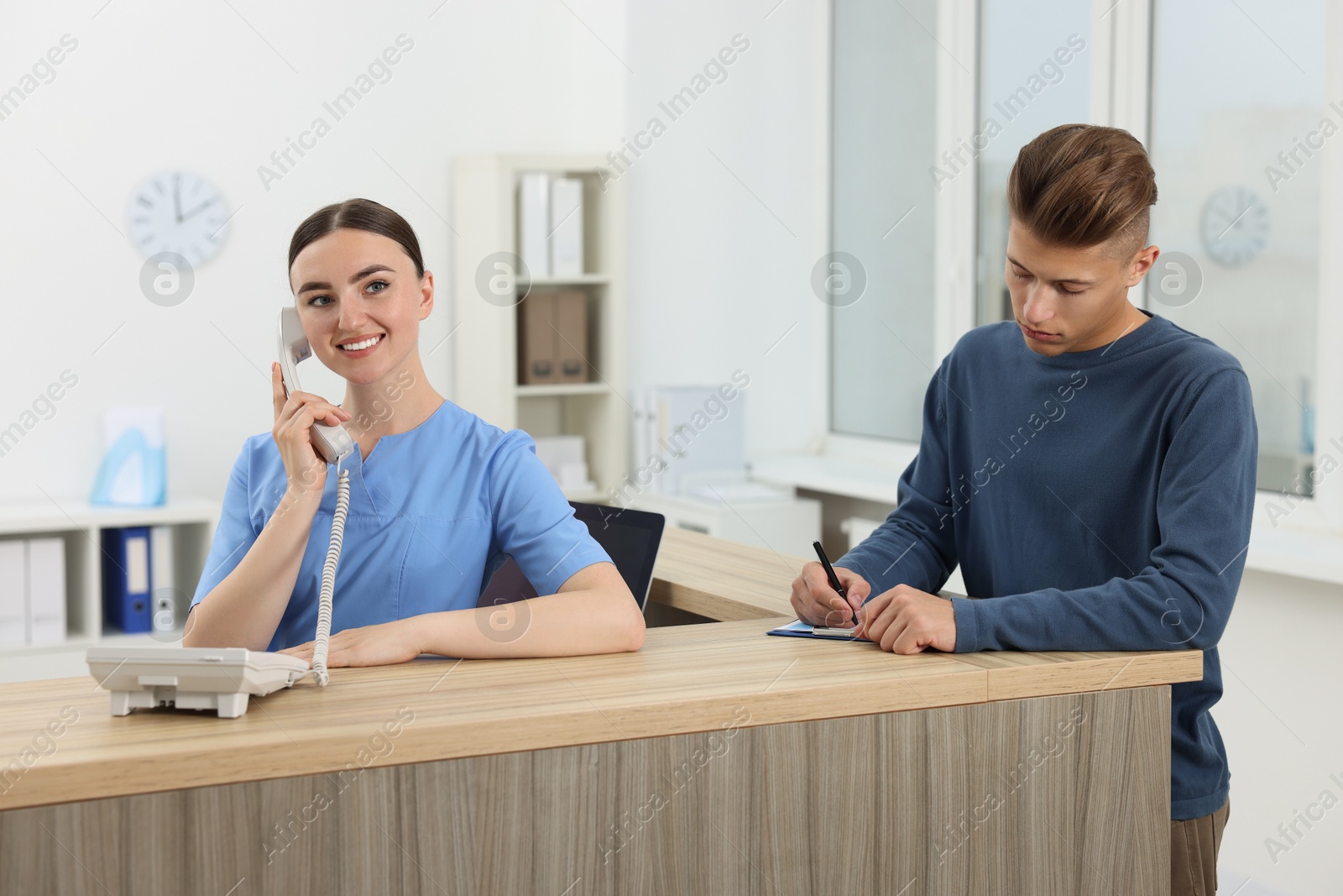 Photo of Professional receptionist working with patient at wooden desk in hospital