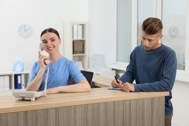 Photo of Professional receptionist working with patient at wooden desk in hospital