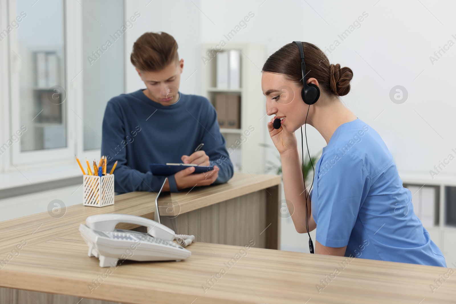 Photo of Professional receptionist working with patient at wooden desk in hospital