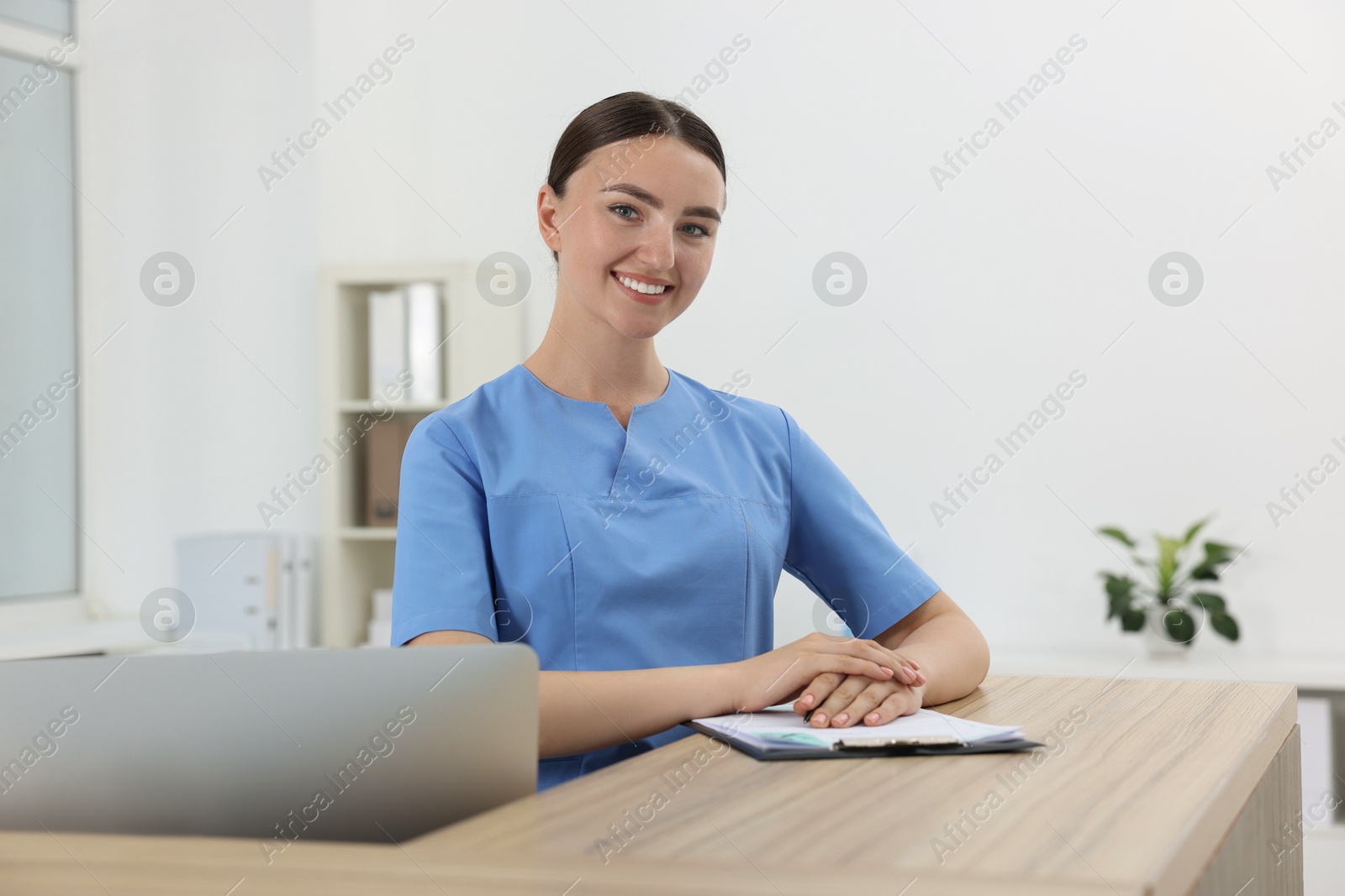 Photo of Professional receptionist working at wooden desk in hospital