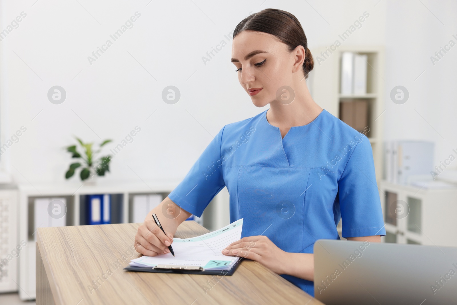 Photo of Professional receptionist working at wooden desk in hospital