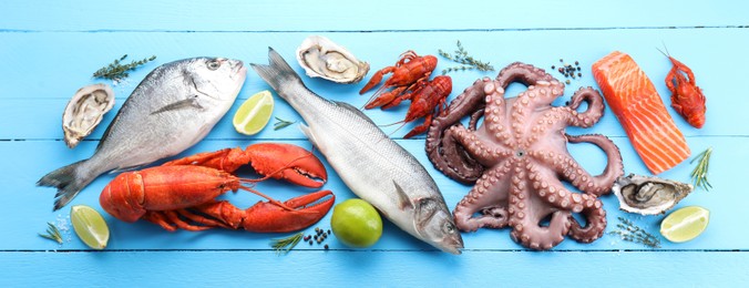 Image of Many different fresh sea food on light blue wooden table, flat lay. Banner design