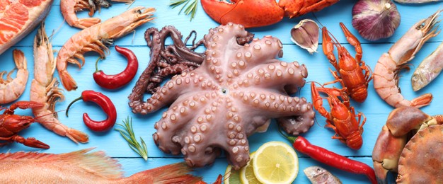 Image of Many different fresh sea food on light blue wooden table, flat lay. Banner design