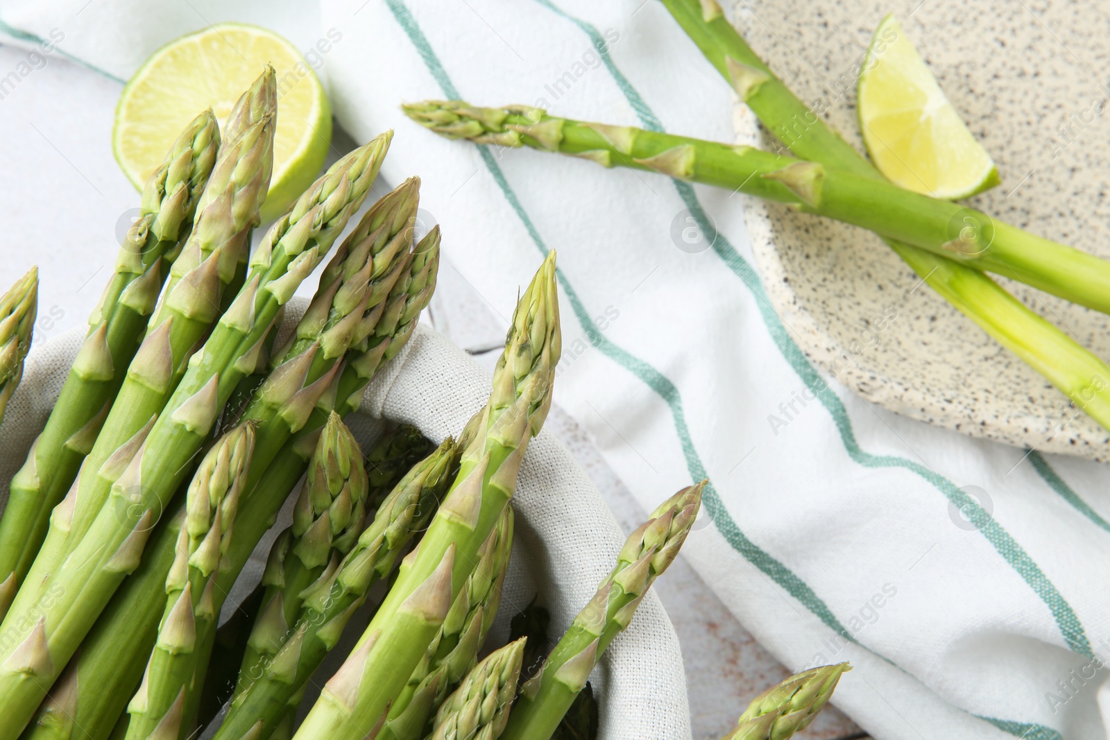 Photo of Fresh green asparagus stems and lime on table, flat lay