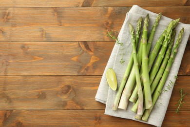 Photo of Fresh green asparagus stems and lime on wooden table, top view. Space for text