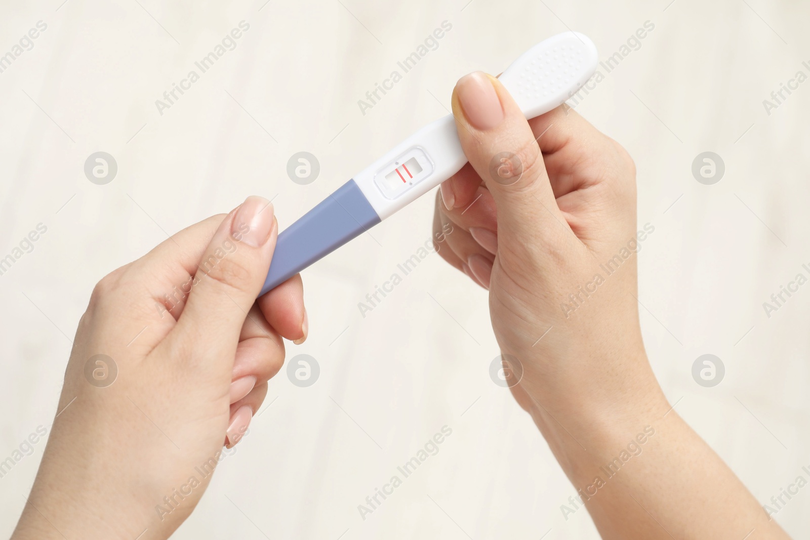 Photo of Woman holding positive pregnancy test indoors, closeup view