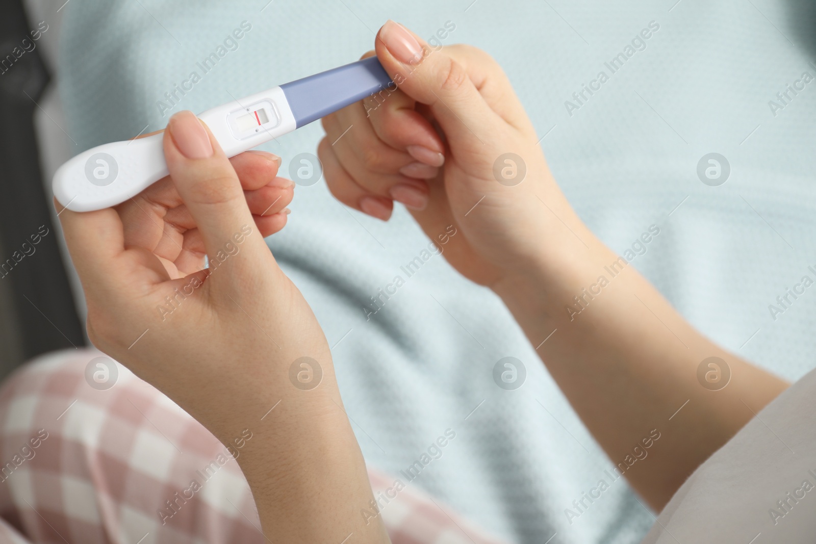 Photo of Woman holding negative pregnancy test indoors, closeup view