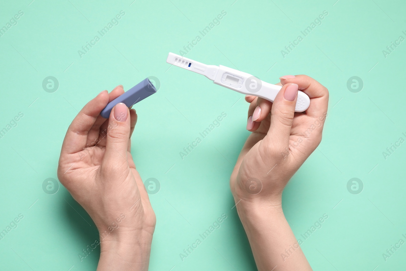 Photo of Woman holding pregnancy test on turquoise background, top view