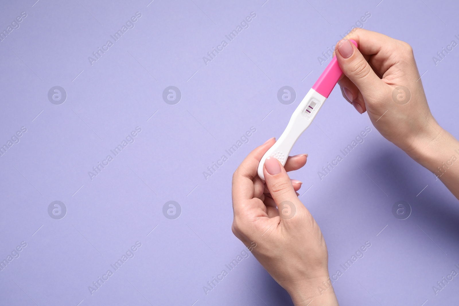 Photo of Woman holding pregnancy test on violet background, top view. Space for text