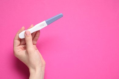 Photo of Woman holding pregnancy test on pink background, top view. Space for text