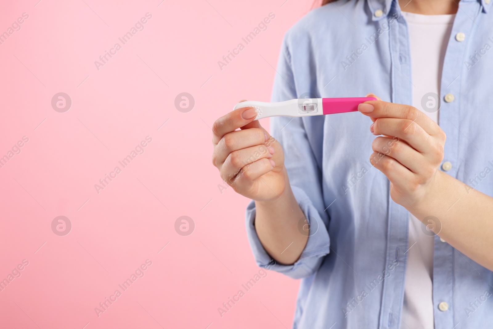 Photo of Woman holding pregnancy test on pink background, closeup. Space for text