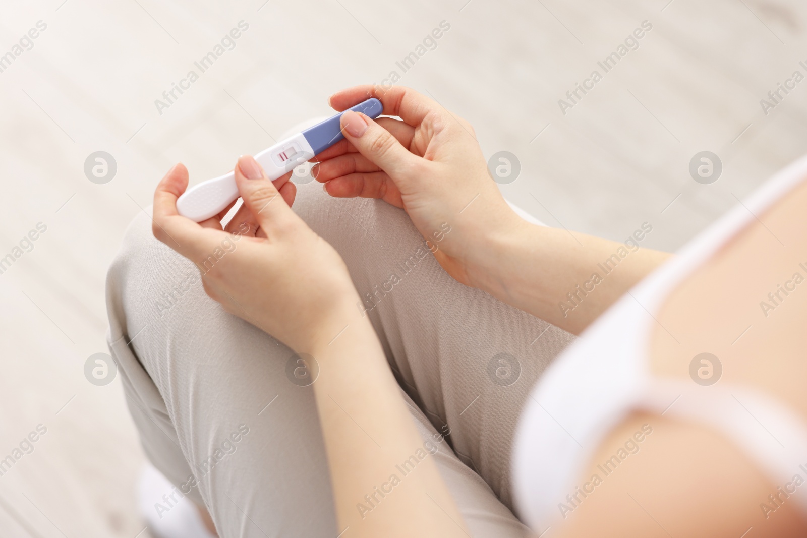 Photo of Woman holding pregnancy test in room, closeup