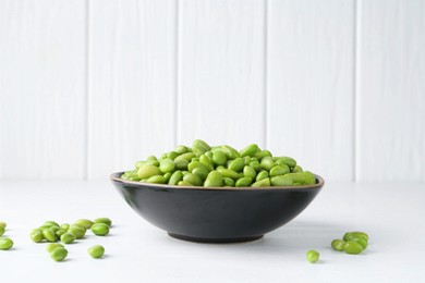 Fresh edamame soybeans in bowl on white wooden table, closeup