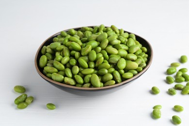 Photo of Fresh edamame soybeans in bowl on white wooden table, closeup