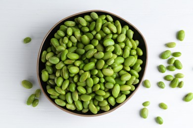 Photo of Fresh edamame soybeans in bowl on white wooden table, top view