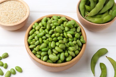 Photo of Fresh edamame soybeans, pods and seeds on white wooden table, closeup