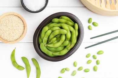 Photo of Fresh edamame pods, soybeans, salt and seeds on white wooden table, flat lay