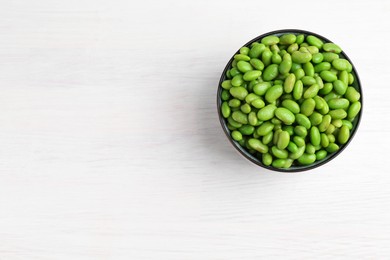 Fresh edamame soybeans in bowl on white wooden table, top view. Space for text