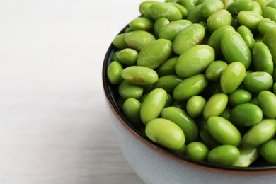 Fresh edamame soybeans in bowl on white wooden table, closeup. Space for text