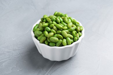 Fresh edamame soybeans in bowl on grey textured table, closeup