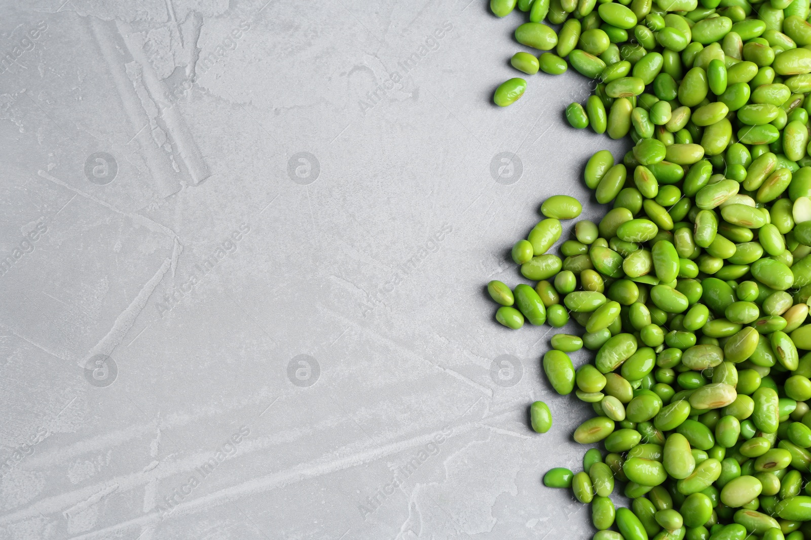 Photo of Fresh edamame soybeans on grey textured table, top view. Space for text