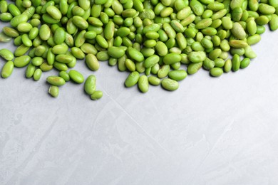 Photo of Fresh edamame soybeans on grey textured table, above view. Space for text