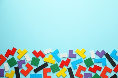 Photo of Colorful wooden puzzle pieces on light blue background, top view. Space for text