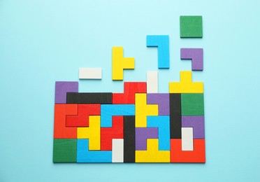 Photo of Colorful wooden puzzle pieces on light blue background, top view