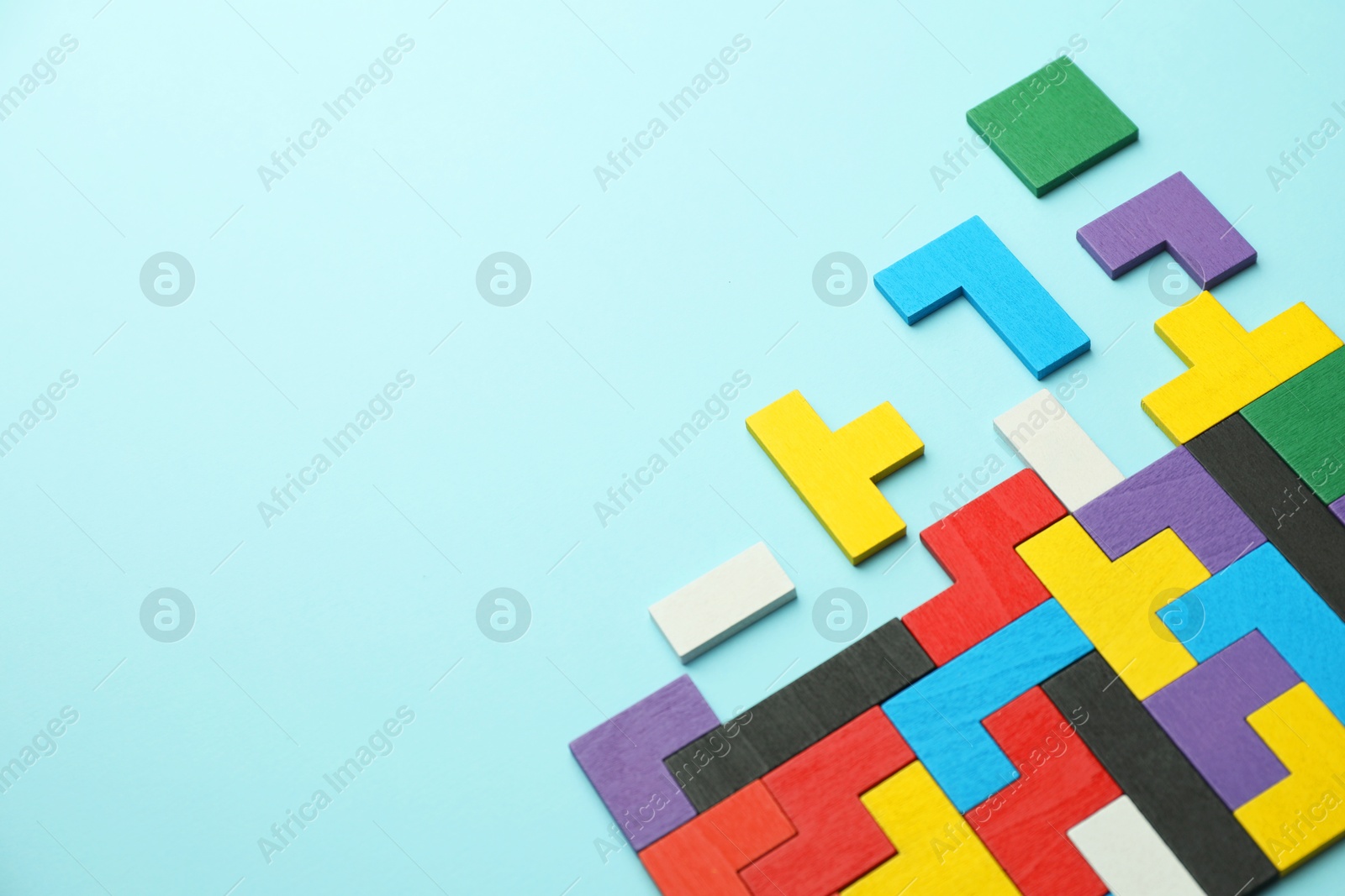 Photo of Colorful wooden puzzle pieces on light blue background, above view. Space for text