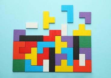 Photo of Colorful wooden puzzle pieces on light blue background, top view