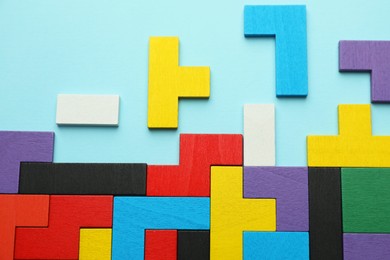 Photo of Colorful wooden puzzle pieces on light blue background, top view