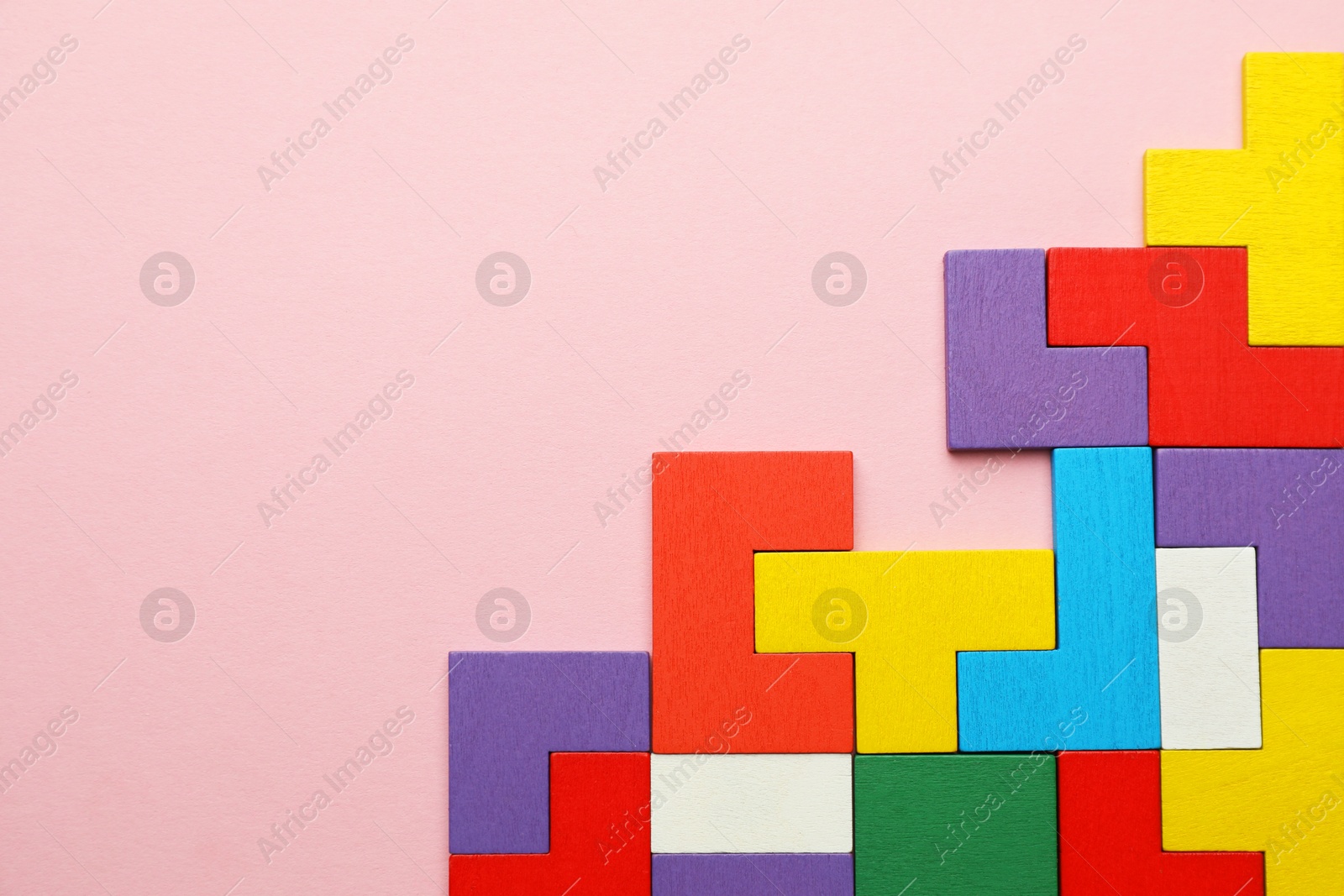 Photo of Colorful wooden puzzle pieces on pink background, top view. Space for text