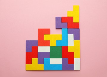 Photo of Colorful wooden puzzle pieces on pink background, top view