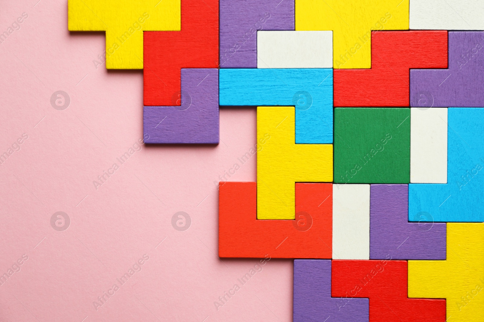 Photo of Colorful wooden puzzle pieces on pink background, top view. Space for text