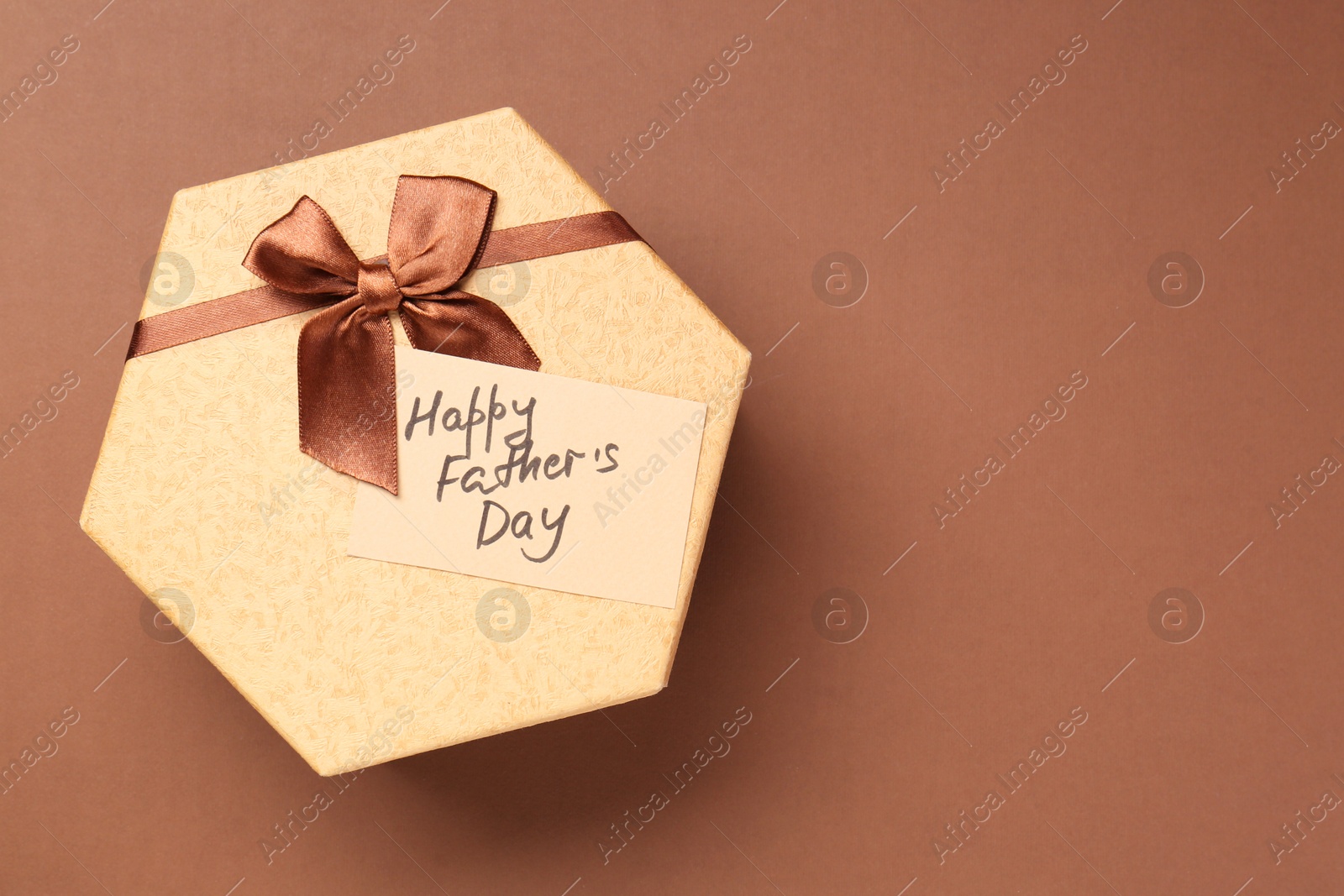 Photo of Card with phrase Happy Father's Day and gift box on light brown background, top view. Space for text