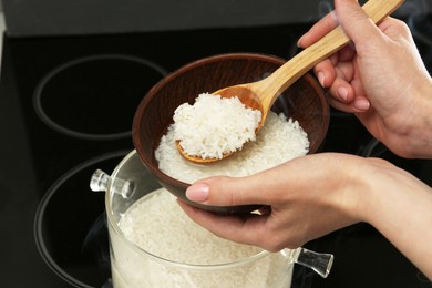 Photo of Woman taking boiled rice into bowl, closeup